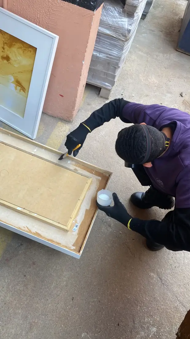 Técnico da D.Lucca com luvas e máscara aplicando produto de dedetização em uma moldura